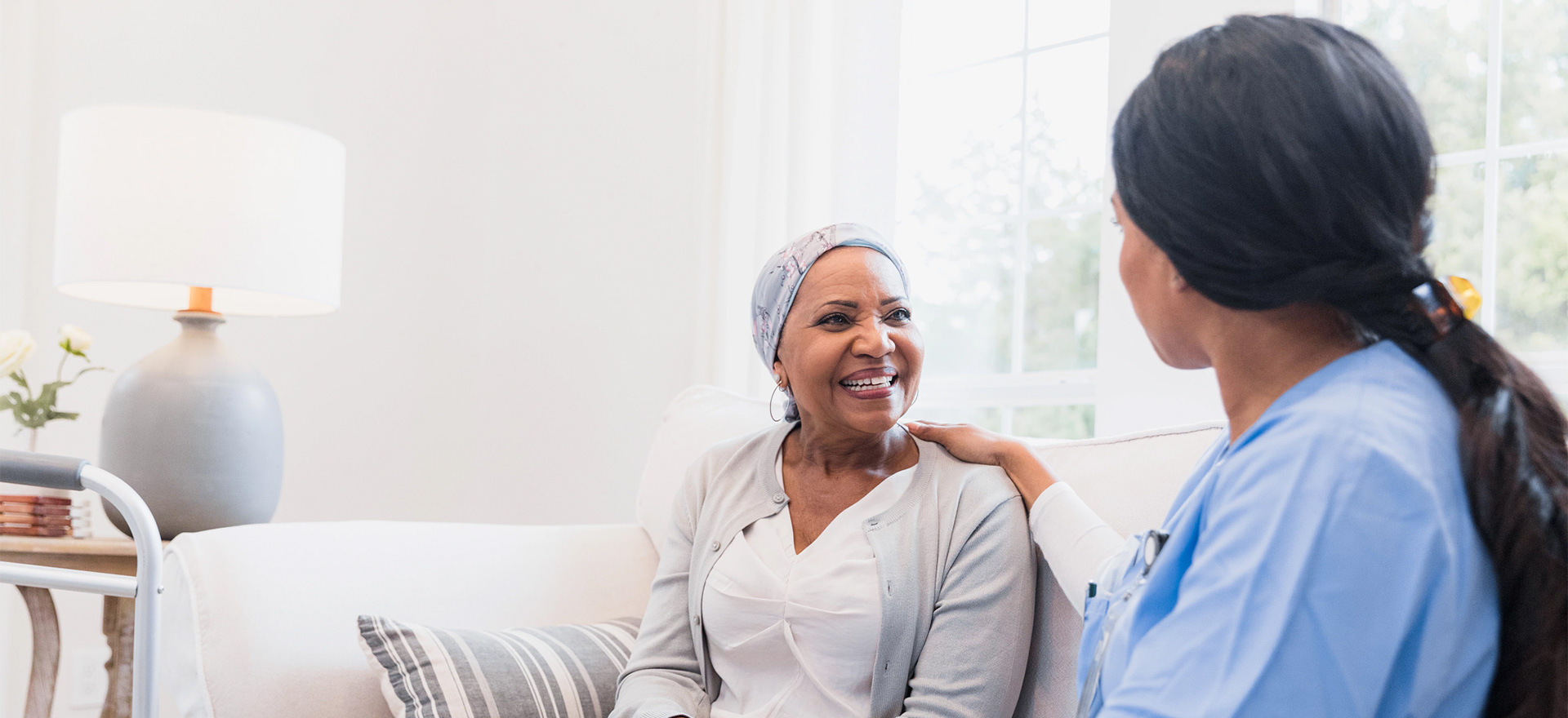 Home health nurse sits with senior patient in their home