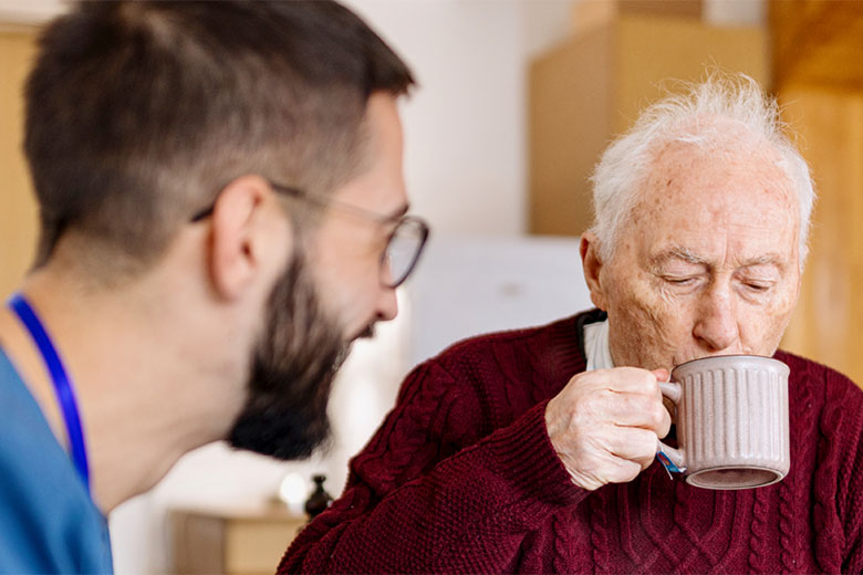 Man sipping coffee with health care worker
